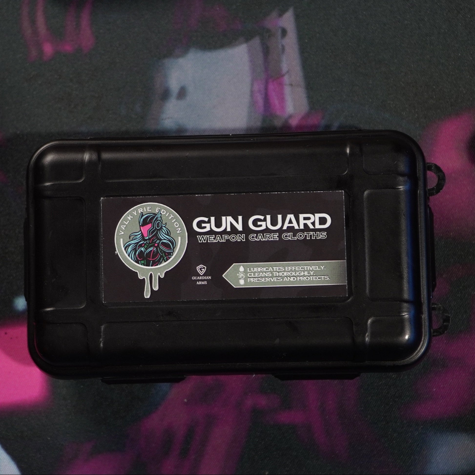 Black gun case labeled 'Gun Guard' with cleaning items on a dark surface.
